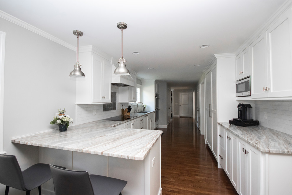 Inspiration for a large transitional galley dark wood floor and brown floor eat-in kitchen remodel in Boston with an undermount sink, shaker cabinets, white cabinets, granite countertops, white backsplash, brick backsplash, stainless steel appliances, a peninsula and white countertops