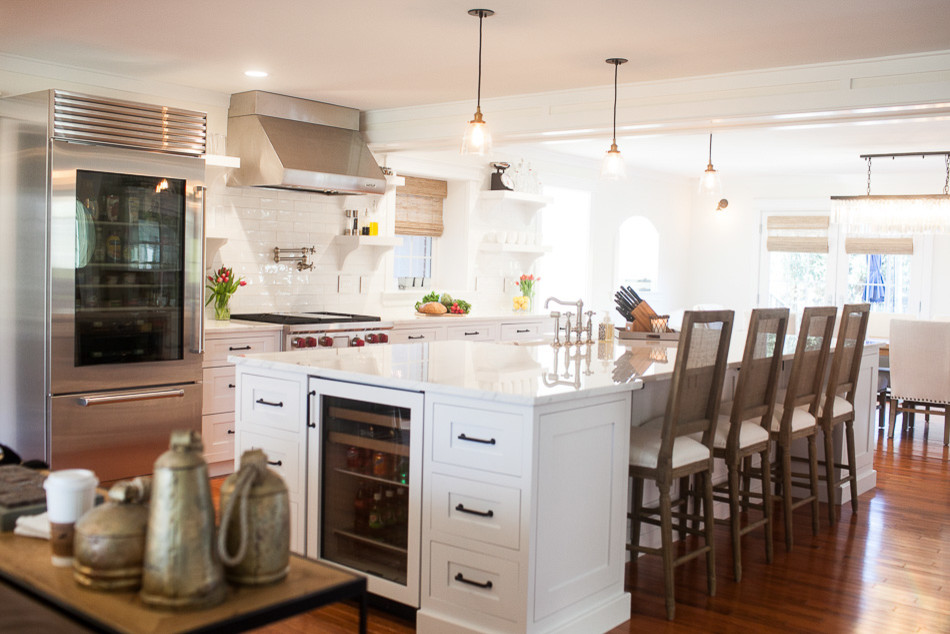 Example of a mid-sized transitional medium tone wood floor eat-in kitchen design in St Louis with a farmhouse sink, flat-panel cabinets, white cabinets, onyx countertops, white backsplash, subway tile backsplash, stainless steel appliances and an island