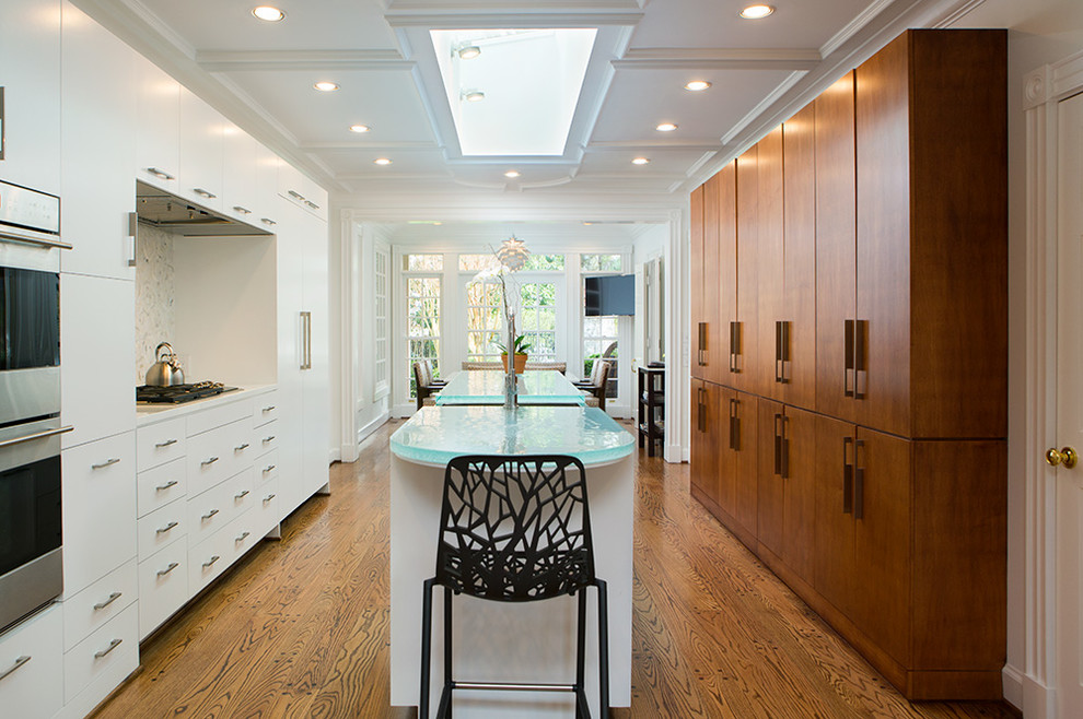 Exemple d'une cuisine chic avec un placard à porte plane, des portes de placard blanches, un électroménager en acier inoxydable et un sol en bois brun.