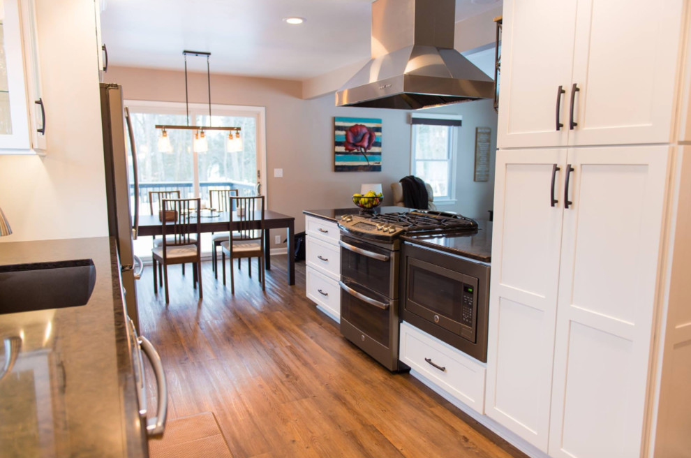 Klassisk inredning av ett mellanstort kök, med en undermonterad diskho, skåp i shakerstil, vita skåp, marmorbänkskiva, stänkskydd med metallisk yta, stänkskydd i mosaik, rostfria vitvaror, mellanmörkt trägolv, en halv köksö och brunt golv