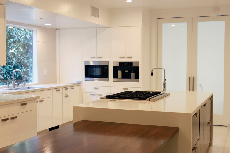 Photo of a large modern galley kitchen/diner in Los Angeles with flat-panel cabinets, white cabinets and multiple islands.