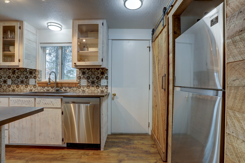 Foto på ett mellanstort rustikt svart kök, med en undermonterad diskho, luckor med glaspanel, skåp i slitet trä, flerfärgad stänkskydd, stänkskydd i keramik, rostfria vitvaror, laminatgolv, en köksö, brunt golv och granitbänkskiva