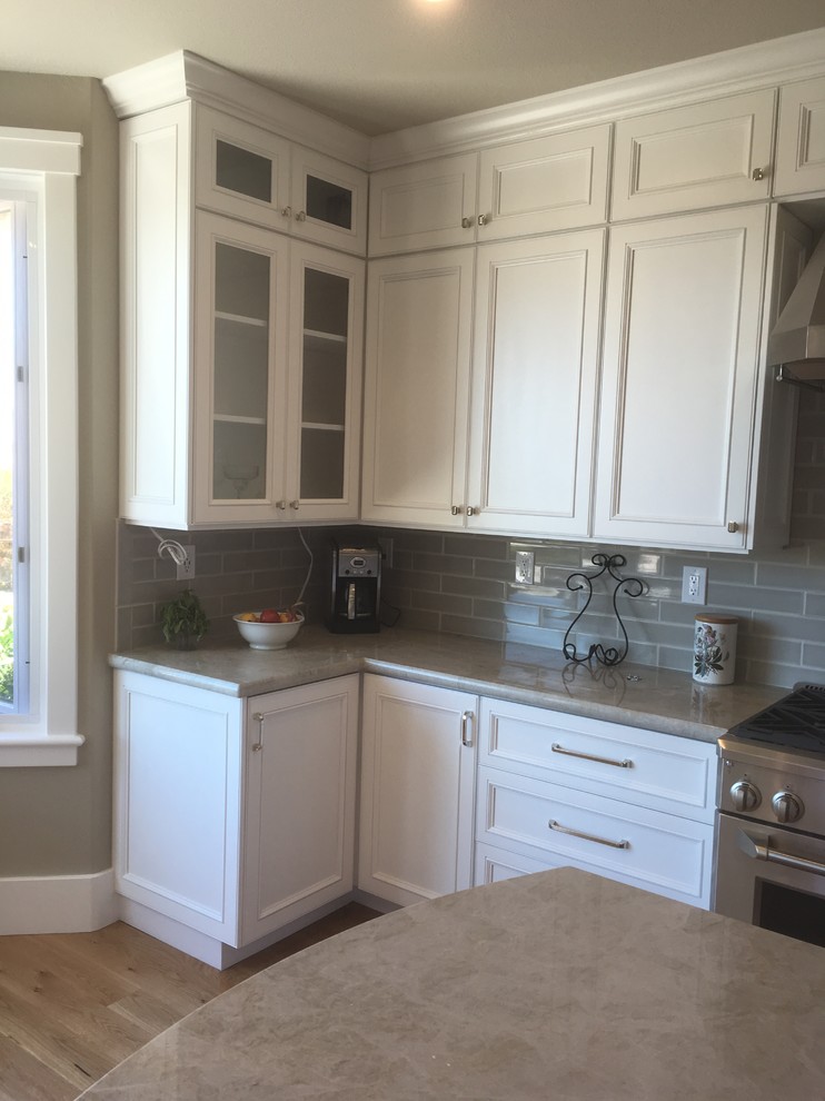 Exempel på ett mycket stort modernt kök, med en rustik diskho, luckor med infälld panel, vita skåp, marmorbänkskiva, grönt stänkskydd, stänkskydd i tunnelbanekakel, rostfria vitvaror, mellanmörkt trägolv, flera köksöar och beiget golv