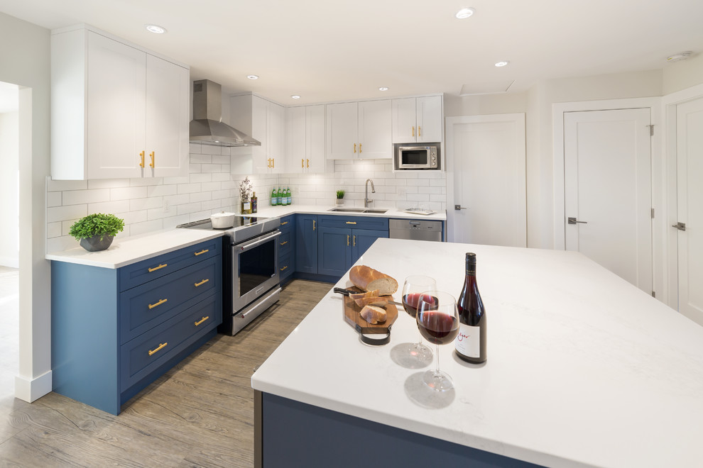 Inspiration for a mid-sized timeless vinyl floor eat-in kitchen remodel in Vancouver with a double-bowl sink, recessed-panel cabinets, blue cabinets, solid surface countertops, white backsplash, subway tile backsplash, stainless steel appliances and an island