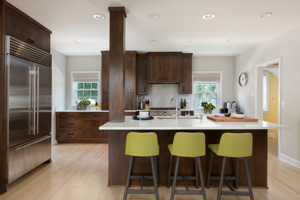 Large transitional u-shaped light wood floor kitchen photo in Milwaukee with an undermount sink, flat-panel cabinets, dark wood cabinets, quartz countertops, white backsplash, ceramic backsplash, stainless steel appliances and an island