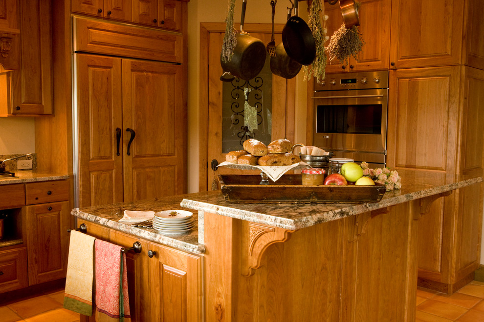Idées déco pour une cuisine craftsman en bois brun de taille moyenne avec un placard avec porte à panneau surélevé, un plan de travail en granite, un électroménager en acier inoxydable, tomettes au sol, îlot et un sol marron.