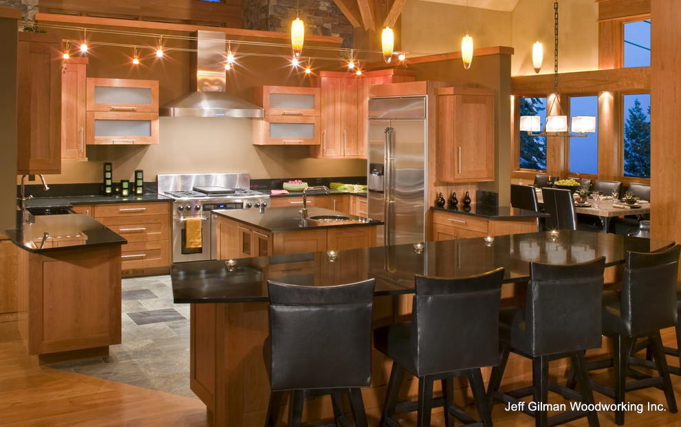 Immagine di una cucina minimalista con lavello sottopiano, ante lisce, ante in legno chiaro, top in granito, elettrodomestici in acciaio inossidabile, paraspruzzi nero e paraspruzzi in lastra di pietra