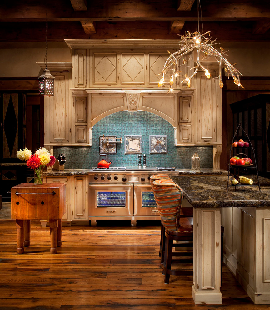 Foto de cocina rústica con puertas de armario beige, salpicadero azul y electrodomésticos de acero inoxidable