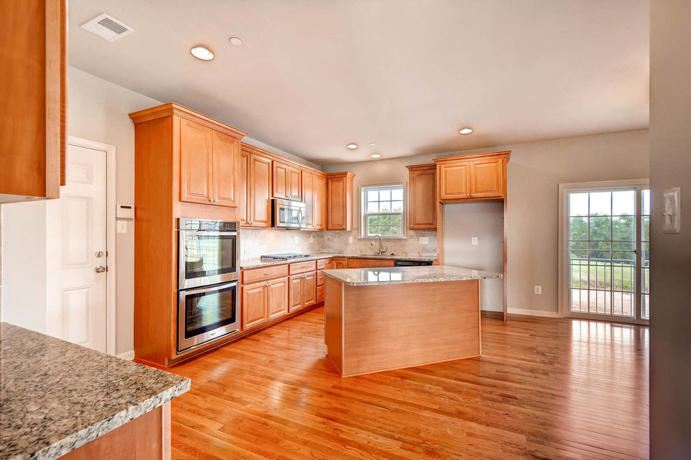 Inspiration for a large timeless l-shaped medium tone wood floor and brown floor enclosed kitchen remodel in Baltimore with raised-panel cabinets, light wood cabinets, granite countertops, gray backsplash, ceramic backsplash, stainless steel appliances and an island