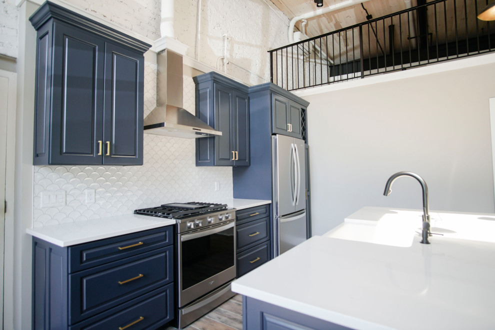 Idéer för att renovera ett mellanstort industriellt vit linjärt vitt kök med öppen planlösning, med en nedsänkt diskho, luckor med upphöjd panel, blå skåp, granitbänkskiva, vitt stänkskydd, stänkskydd i marmor, rostfria vitvaror, vinylgolv, en köksö och brunt golv