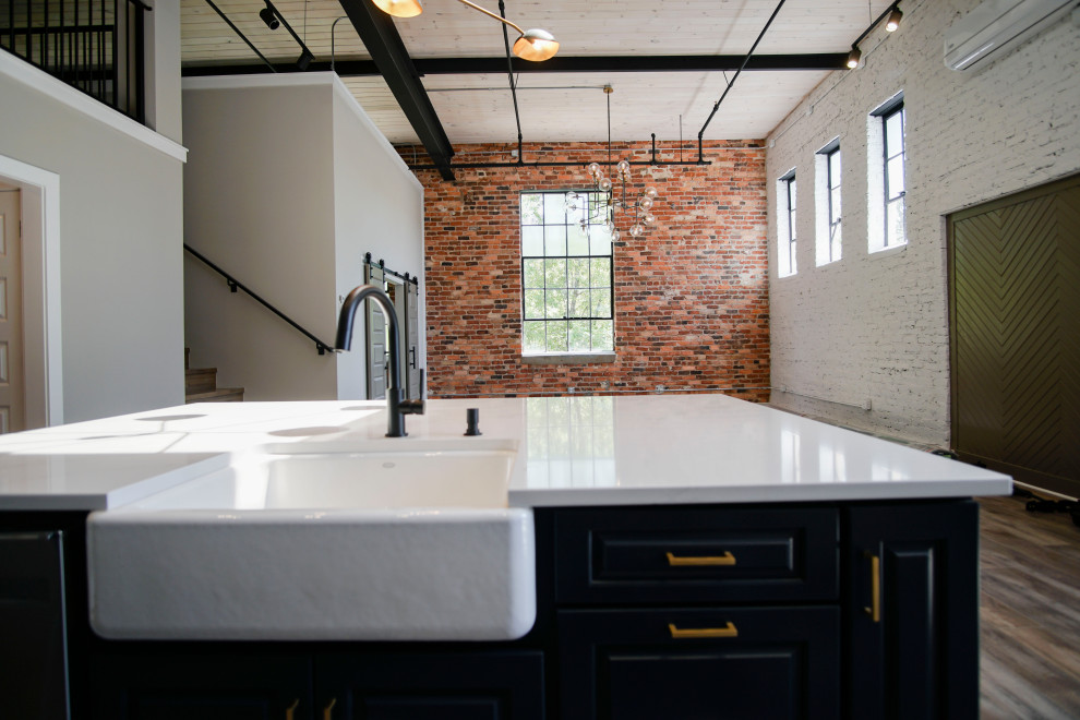 Foto på ett mellanstort industriellt vit linjärt kök med öppen planlösning, med en nedsänkt diskho, luckor med upphöjd panel, blå skåp, granitbänkskiva, vitt stänkskydd, stänkskydd i marmor, rostfria vitvaror, vinylgolv, en köksö och brunt golv