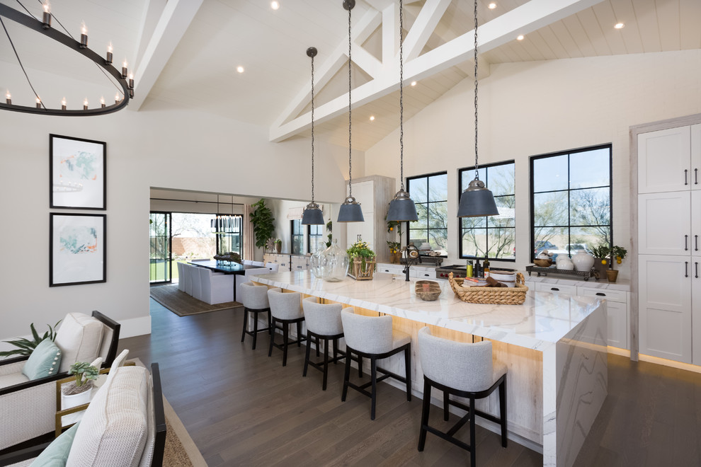 Large trendy galley dark wood floor and brown floor open concept kitchen photo in Phoenix with shaker cabinets, white cabinets, an island, white countertops, an undermount sink, quartz countertops and paneled appliances