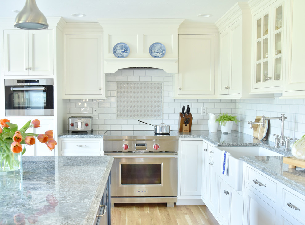 Example of a classic light wood floor kitchen design in Boston with a farmhouse sink, recessed-panel cabinets, granite countertops, ceramic backsplash, an island and blue countertops