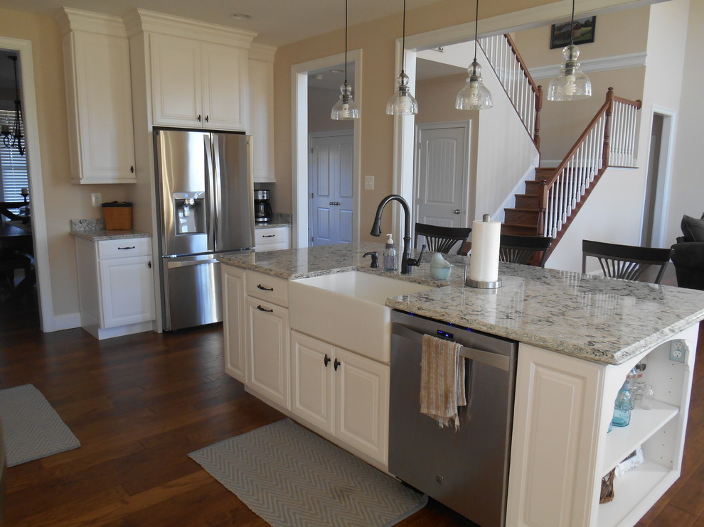 Large transitional u-shaped medium tone wood floor and brown floor open concept kitchen photo in Baltimore with raised-panel cabinets, white cabinets, granite countertops, stainless steel appliances, an island and a farmhouse sink