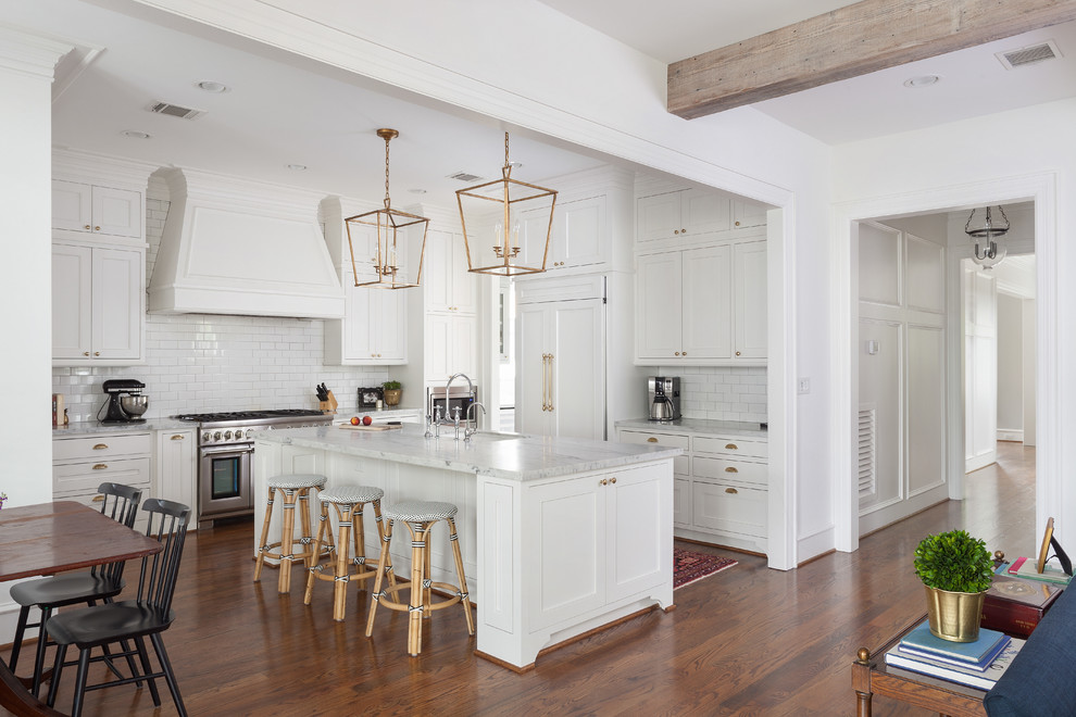Huge trendy u-shaped medium tone wood floor, brown floor and exposed beam enclosed kitchen photo in Houston with an undermount sink, shaker cabinets, white cabinets, marble countertops, white backsplash, subway tile backsplash, stainless steel appliances, an island and gray countertops