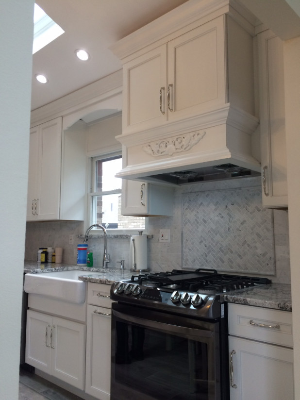 This is an example of a medium sized classic l-shaped enclosed kitchen in New York with a belfast sink, recessed-panel cabinets, white cabinets, granite worktops, white splashback, marble splashback, black appliances, porcelain flooring and no island.