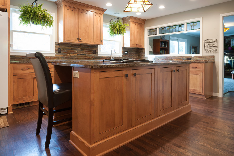 Inspiration for a mid-sized craftsman l-shaped medium tone wood floor eat-in kitchen remodel in Indianapolis with an undermount sink, shaker cabinets, medium tone wood cabinets, granite countertops, multicolored backsplash, stone tile backsplash, stainless steel appliances and an island