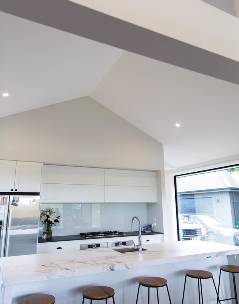 Exempel på ett mellanstort modernt linjärt kök och matrum, med en undermonterad diskho, luckor med profilerade fronter, vita skåp, marmorbänkskiva, vitt stänkskydd, glaspanel som stänkskydd, rostfria vitvaror, mörkt trägolv och en köksö
