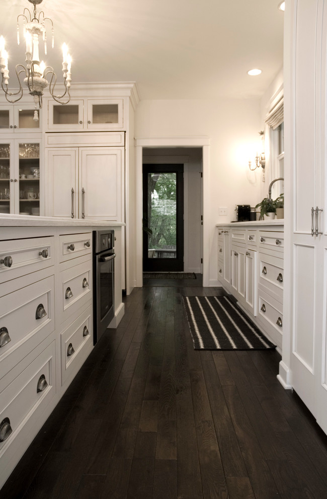 Inspiration for a mid-sized transitional l-shaped dark wood floor open concept kitchen remodel in Minneapolis with an undermount sink, beaded inset cabinets, white cabinets, granite countertops, white backsplash, paneled appliances and an island