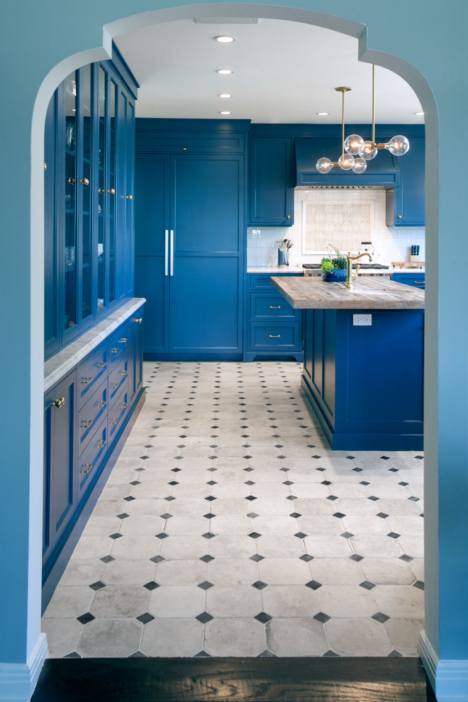 Inspiration för stora medelhavsstil u-kök, med luckor med infälld panel, blå skåp, marmorbänkskiva, vitt stänkskydd, stänkskydd i tunnelbanekakel, integrerade vitvaror, en köksö och flerfärgat golv