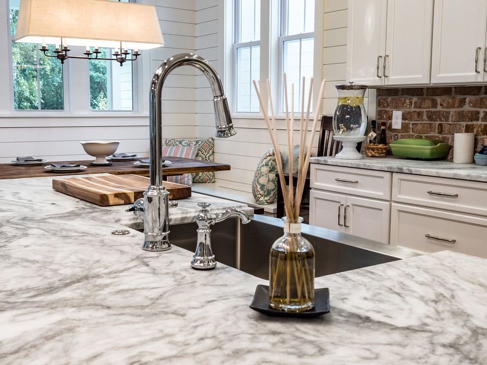 Foto på ett mellanstort lantligt vit kök, med en rustik diskho, luckor med infälld panel, vita skåp, marmorbänkskiva, rött stänkskydd, stänkskydd i tegel, rostfria vitvaror, mellanmörkt trägolv, en köksö och brunt golv