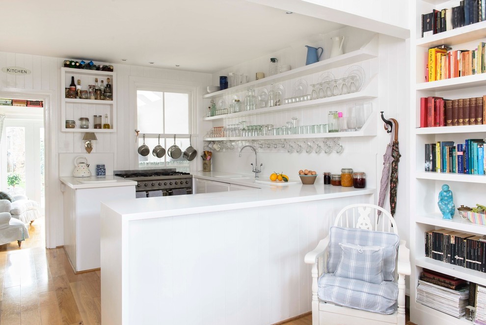 Small beach style u-shaped medium tone wood floor kitchen photo in Kent with open cabinets, white cabinets, a peninsula and stainless steel appliances