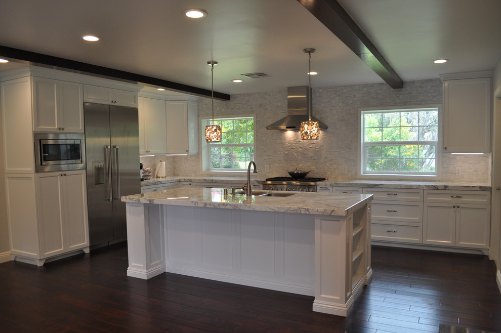 Enclosed kitchen - large transitional u-shaped dark wood floor and brown floor enclosed kitchen idea in Orange County with a double-bowl sink, shaker cabinets, white cabinets, marble countertops, white backsplash, stone tile backsplash, stainless steel appliances and an island
