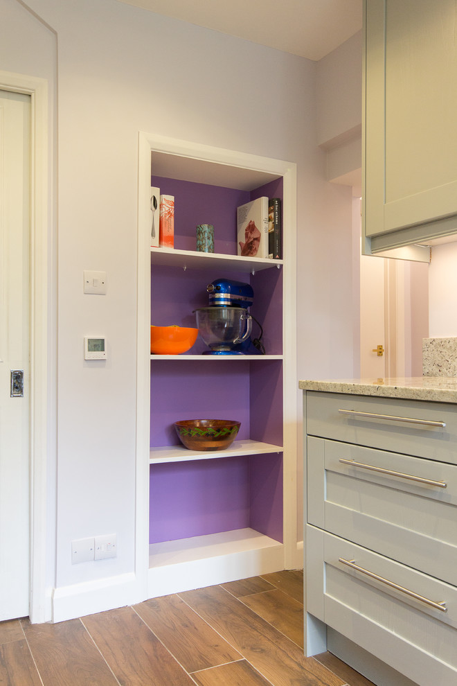 This is an example of a medium sized modern u-shaped enclosed kitchen in London with an integrated sink, shaker cabinets, grey cabinets, granite worktops, pink splashback, glass sheet splashback, stainless steel appliances, porcelain flooring and no island.