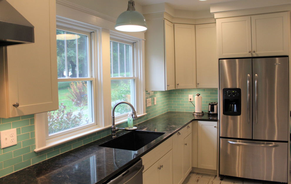 Aménagement d'une grande cuisine américaine parallèle classique avec un plan de travail en granite, une crédence bleue, un électroménager en acier inoxydable, un sol en bois brun et une péninsule.