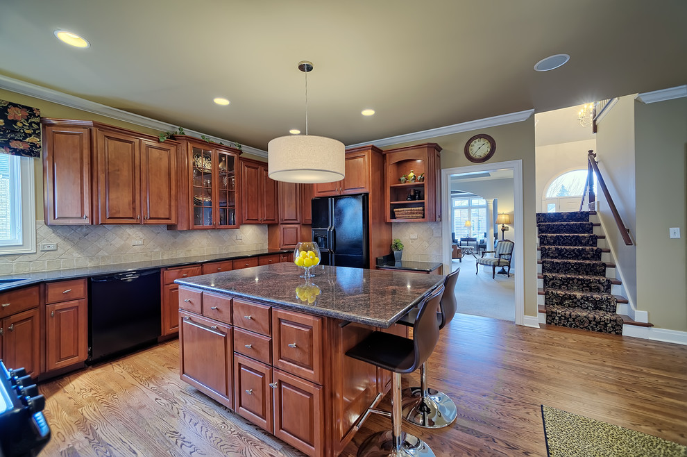 Example of a large classic u-shaped dark wood floor and brown floor eat-in kitchen design in Chicago with an undermount sink, raised-panel cabinets, dark wood cabinets, granite countertops, beige backsplash, travertine backsplash, black appliances and an island