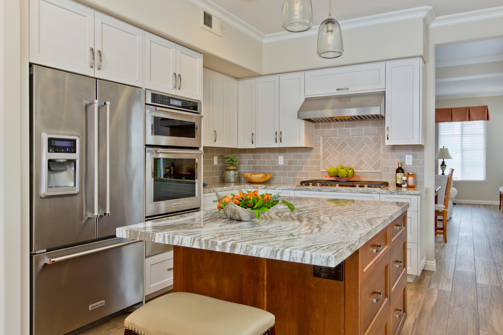 Example of a mid-sized beach style u-shaped ceramic tile open concept kitchen design in San Diego with a farmhouse sink, shaker cabinets, white cabinets, quartz countertops, gray backsplash, ceramic backsplash, stainless steel appliances and an island