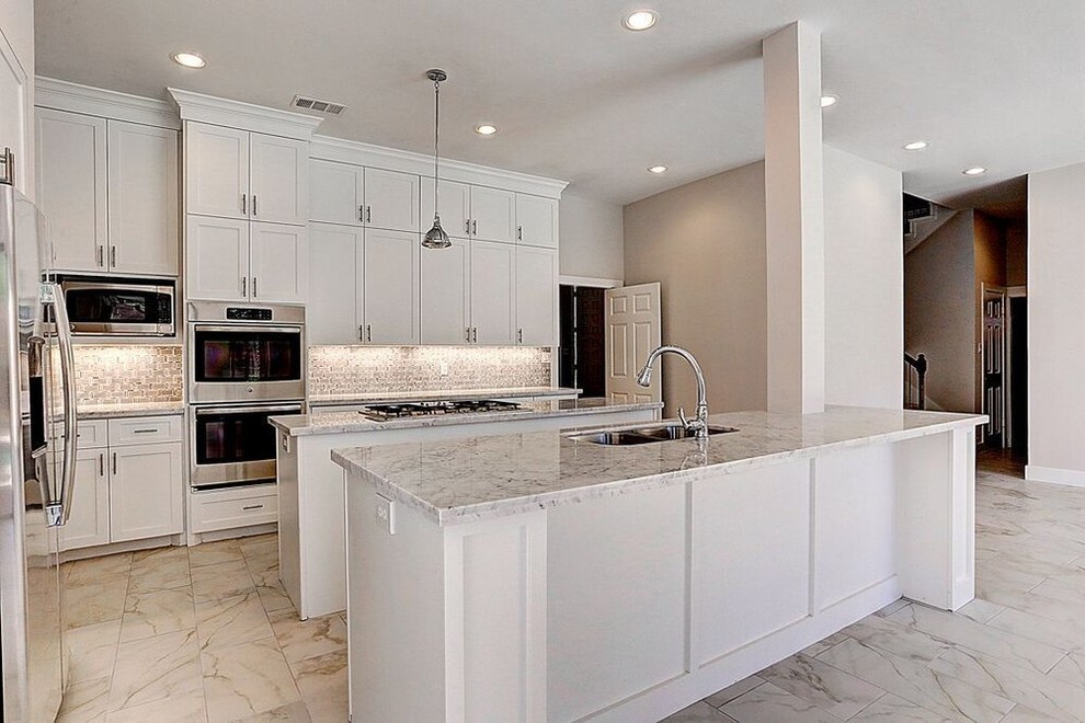 Medium sized contemporary galley open plan kitchen in Houston with a submerged sink, shaker cabinets, white cabinets, granite worktops, stainless steel appliances, porcelain flooring, multiple islands and beige floors.