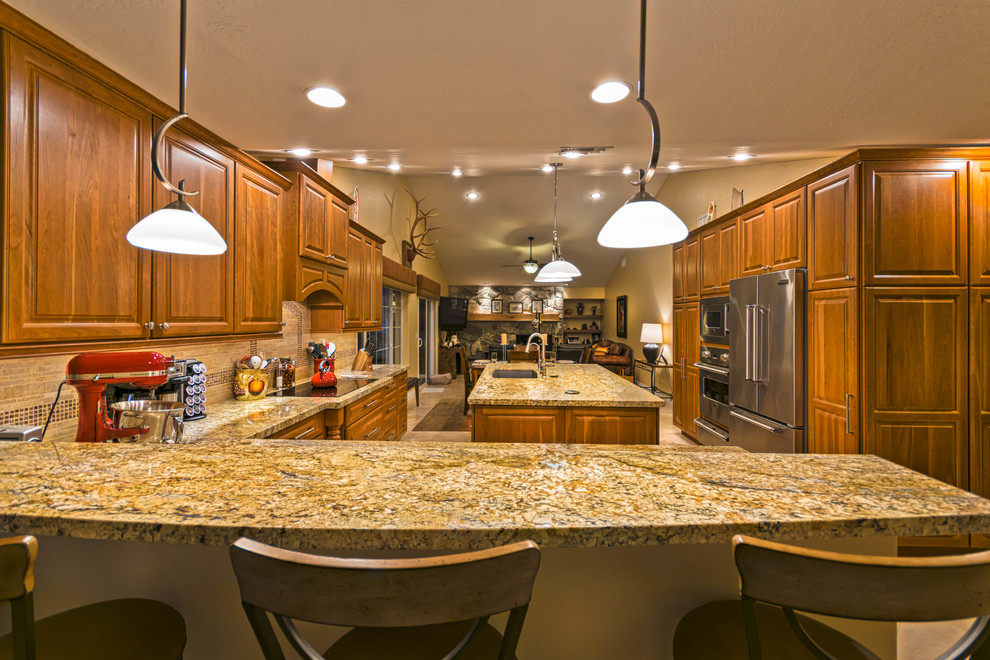 Inspiration for a large transitional u-shaped travertine floor open concept kitchen remodel in Phoenix with an undermount sink, recessed-panel cabinets, medium tone wood cabinets, granite countertops, beige backsplash, stone tile backsplash, stainless steel appliances and an island