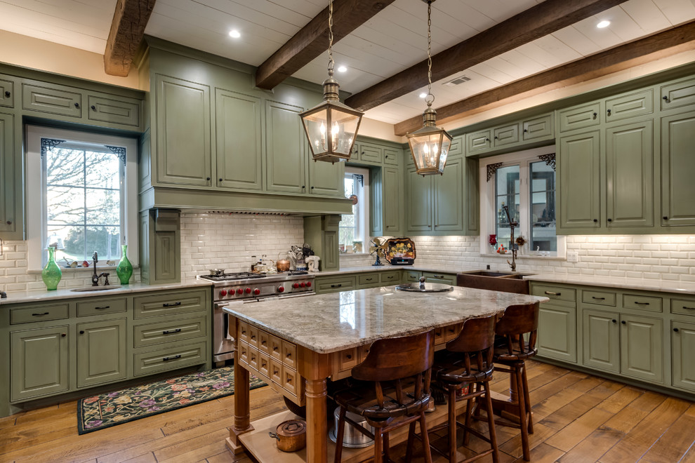 Inspiration for a large classic l-shaped kitchen in Dallas with green cabinets, quartz worktops, white splashback, metro tiled splashback, stainless steel appliances, medium hardwood flooring, an island, brown floors, a belfast sink and raised-panel cabinets.