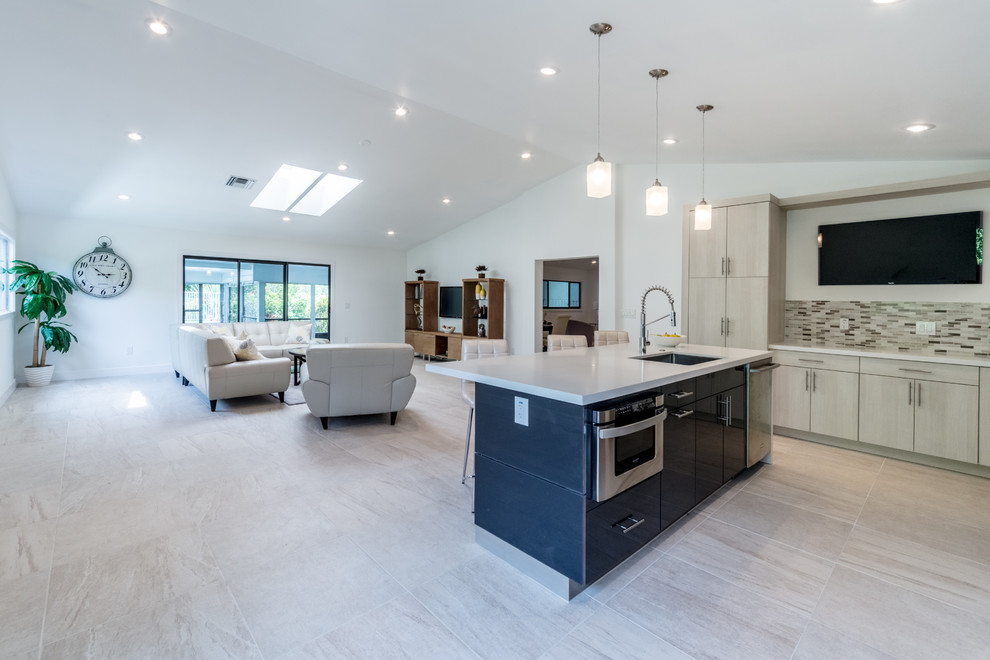 This is an example of a medium sized traditional l-shaped open plan kitchen in Miami with a submerged sink, flat-panel cabinets, light wood cabinets, composite countertops, beige splashback, matchstick tiled splashback, stainless steel appliances, porcelain flooring, an island and beige floors.