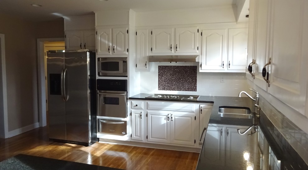 Moderne Küche mit Unterbauwaschbecken, Granit-Arbeitsplatte, Küchengeräten aus Edelstahl und braunem Holzboden in Sonstige
