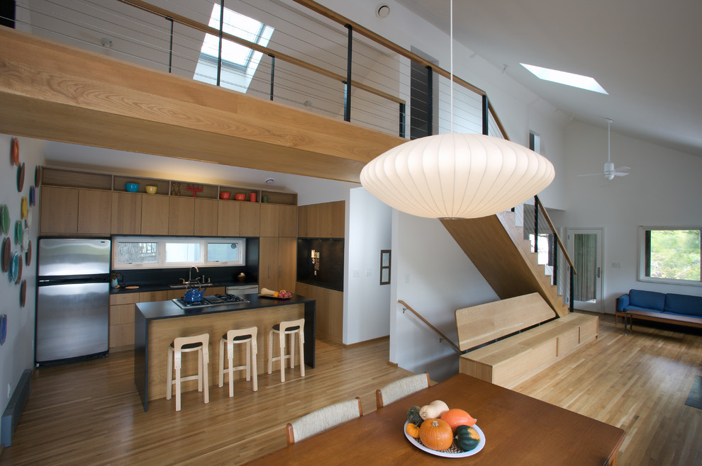 На фото: кухня в стиле модернизм с обеденным столом, плоскими фасадами, светлыми деревянными фасадами и техникой из нержавеющей стали
