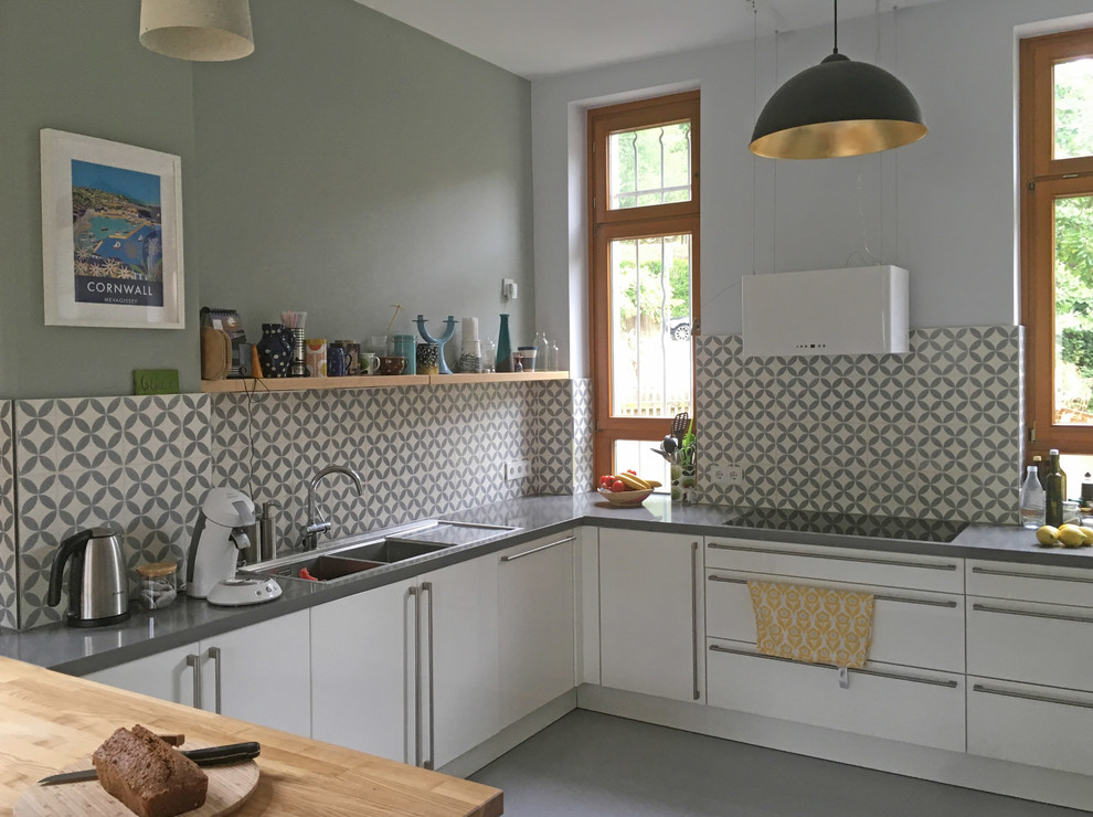 Modern inredning av ett kök, med släta luckor, vita skåp, bänkskiva i kvartsit, grått stänkskydd, stänkskydd i cementkakel, linoleumgolv och grått golv