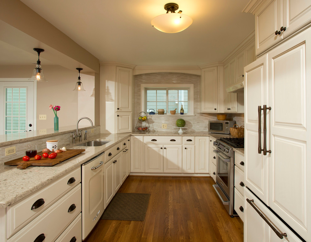 Example of a mid-sized classic u-shaped medium tone wood floor kitchen design in DC Metro with an undermount sink, recessed-panel cabinets, white cabinets, beige backsplash, matchstick tile backsplash, stainless steel appliances and no island