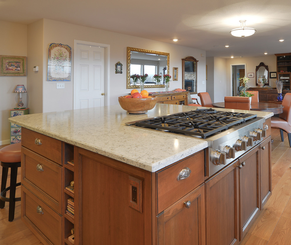 Foto på ett mellanstort vintage kök, med en undermonterad diskho, luckor med infälld panel, bruna skåp, bänkskiva i kvarts, beige stänkskydd, stänkskydd i stenkakel, rostfria vitvaror, mellanmörkt trägolv, en köksö och brunt golv