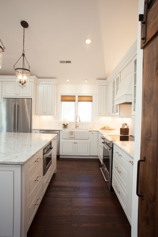 Bild på ett mellanstort vintage l-kök, med en rustik diskho, luckor med profilerade fronter, vita skåp, marmorbänkskiva, vitt stänkskydd, stänkskydd i keramik, rostfria vitvaror, mörkt trägolv och en köksö