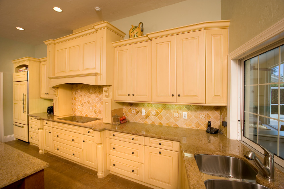 Idéer för att renovera ett stort vintage kök, med luckor med upphöjd panel, gula skåp, granitbänkskiva, flerfärgad stänkskydd, integrerade vitvaror, klinkergolv i porslin, en köksö, en undermonterad diskho, stänkskydd i marmor och beiget golv