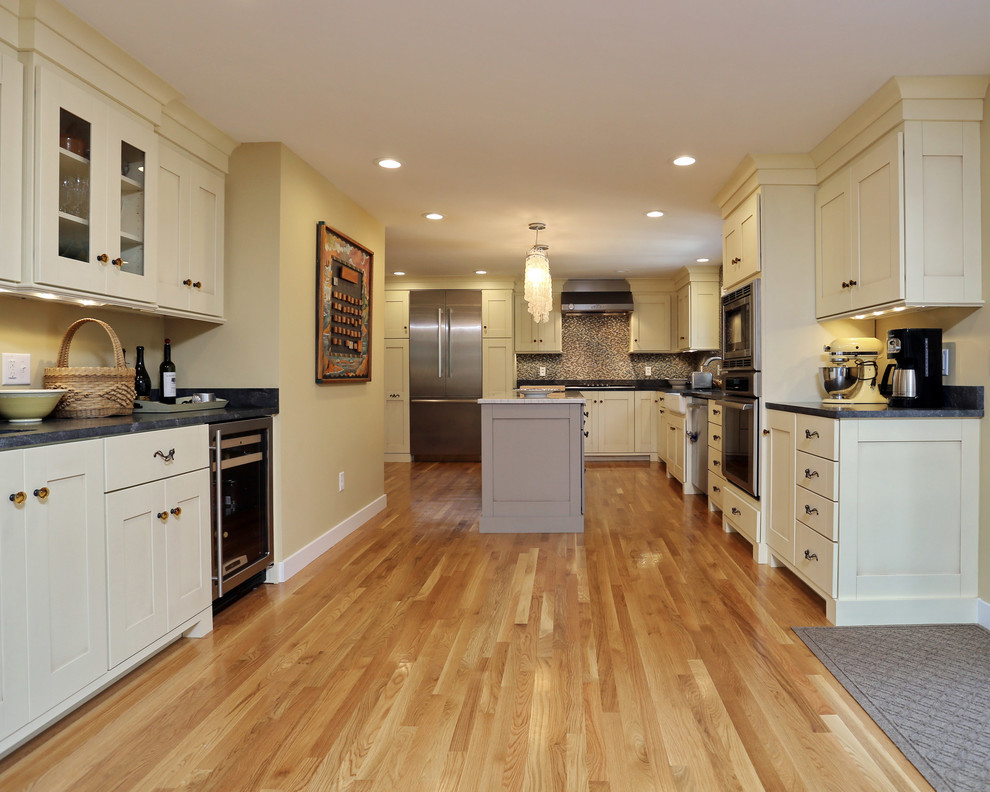 Exempel på ett avskilt, stort klassiskt l-kök, med en rustik diskho, skåp i shakerstil, beige skåp, granitbänkskiva, flerfärgad stänkskydd, rostfria vitvaror, ljust trägolv och en köksö