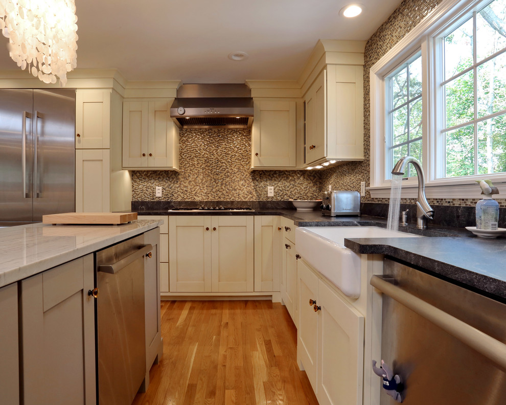 Enclosed kitchen - large traditional l-shaped light wood floor enclosed kitchen idea in Boston with a farmhouse sink, shaker cabinets, beige cabinets, multicolored backsplash, stainless steel appliances and an island