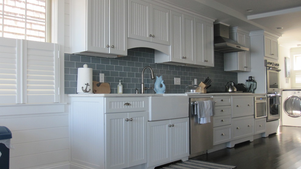 Large beach style galley dark wood floor eat-in kitchen photo in Boston with a farmhouse sink, beaded inset cabinets, white cabinets, granite countertops, gray backsplash, glass tile backsplash, stainless steel appliances and no island