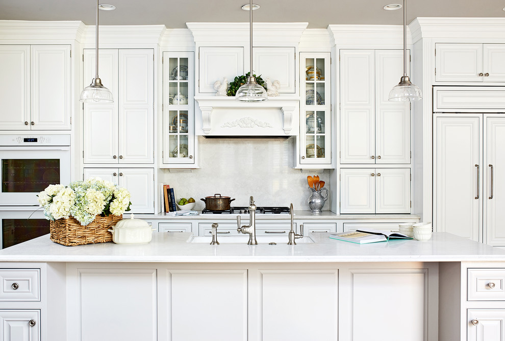 This is an example of a large classic kitchen in DC Metro with white cabinets, white splashback, integrated appliances, an island, white worktops, raised-panel cabinets and stone slab splashback.