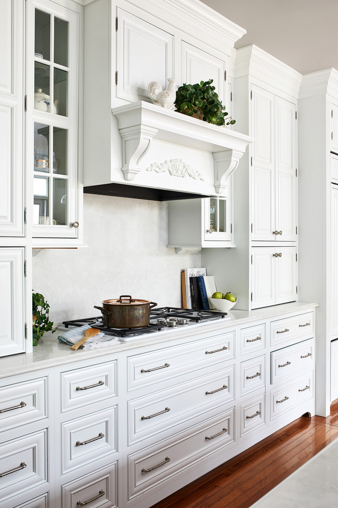 Esempio di una grande cucina tradizionale con ante bianche, paraspruzzi bianco, elettrodomestici da incasso, pavimento in legno massello medio e top bianco