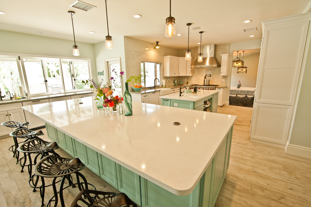Huge beach style u-shaped ceramic tile open concept kitchen photo in Orange County with a farmhouse sink, raised-panel cabinets, white cabinets, quartz countertops, blue backsplash, ceramic backsplash, stainless steel appliances and two islands