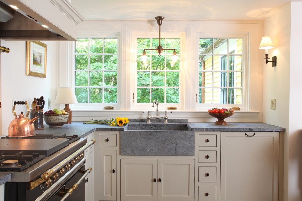 Klassische Wohnküche in L-Form mit Landhausspüle, Kassettenfronten, weißen Schränken, Speckstein-Arbeitsplatte und Küchenrückwand in Weiß in Boston
