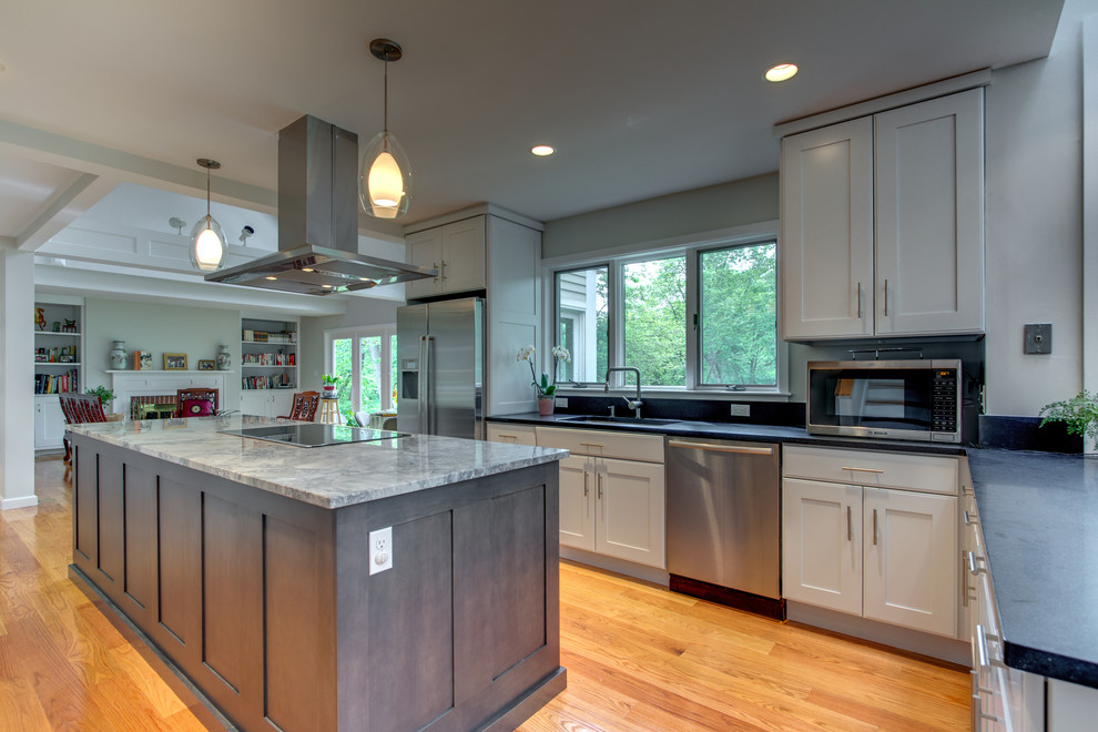 Example of a large transitional l-shaped medium tone wood floor eat-in kitchen design in Boston with an undermount sink, shaker cabinets, gray cabinets, granite countertops, stainless steel appliances and an island